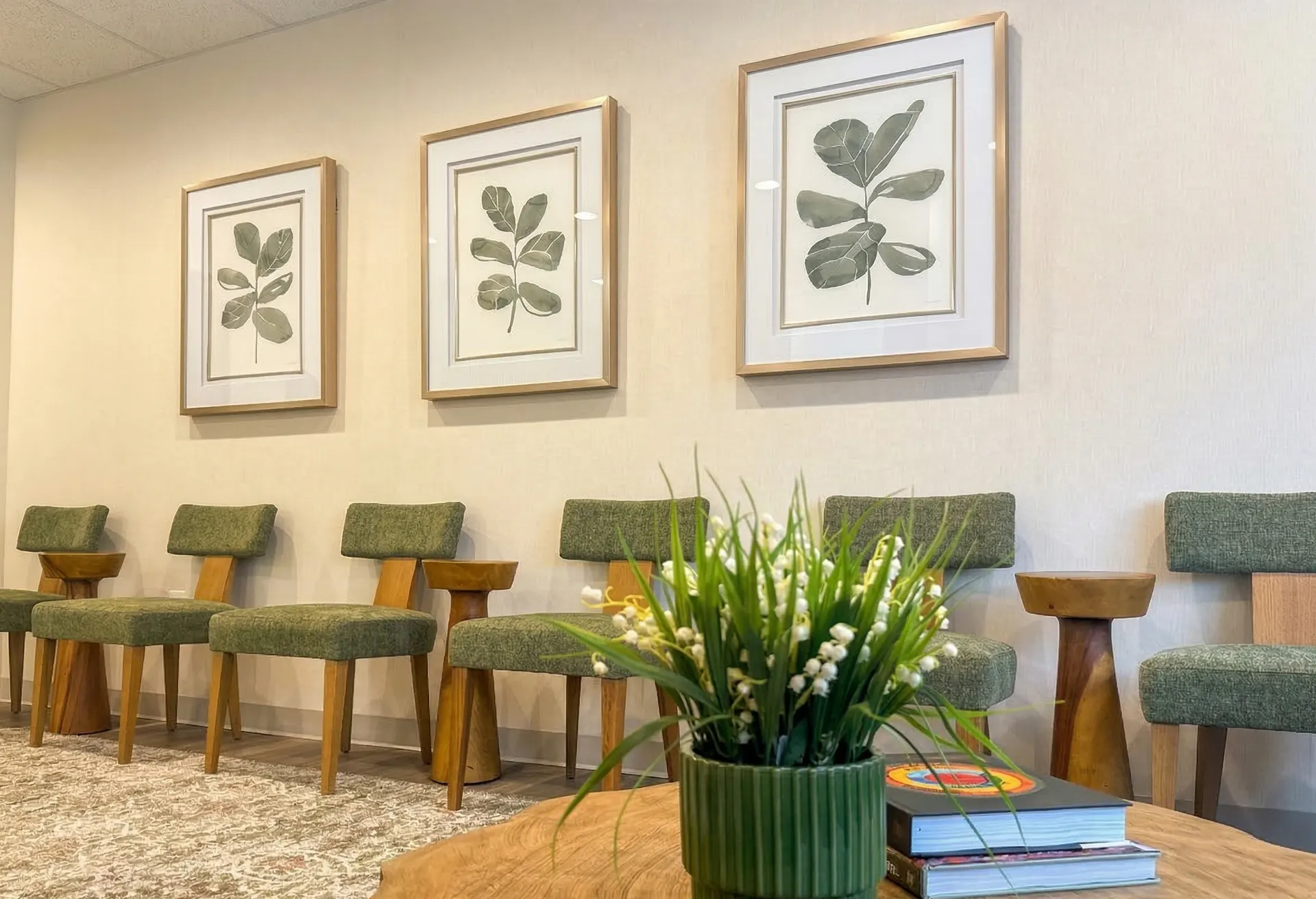 Waiting area with botanical art and green chairs